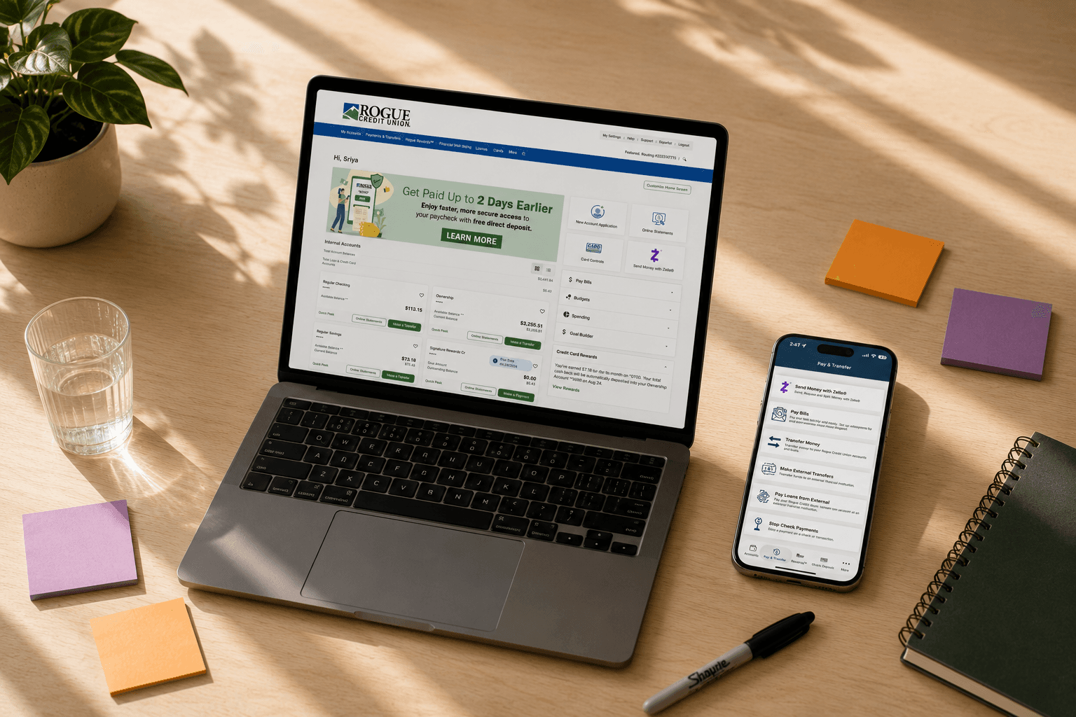 Rogue Credit Union digital banking open on a laptop and phone on a sunlit desk.